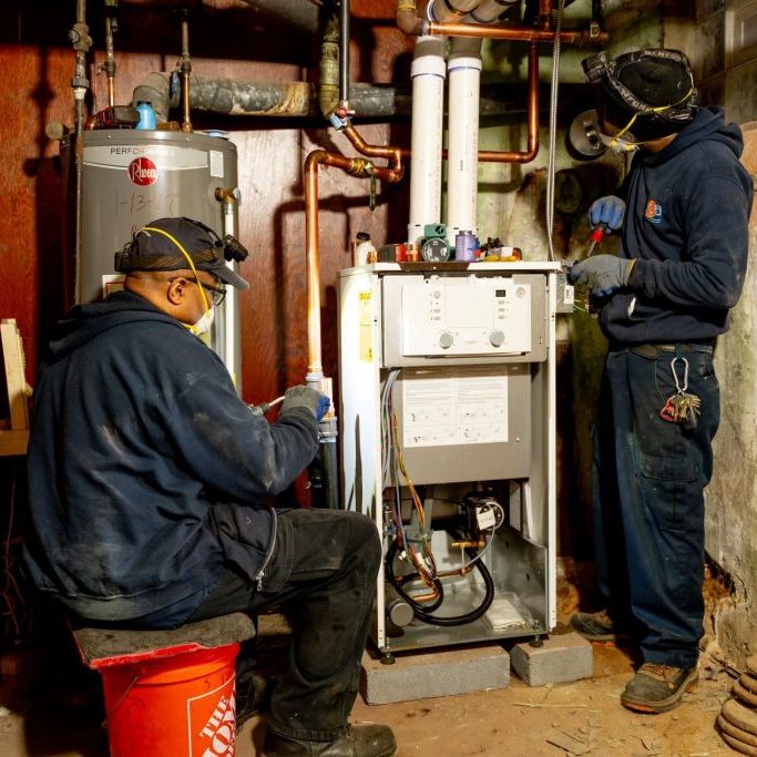 Two ECA employees fixing a heater.