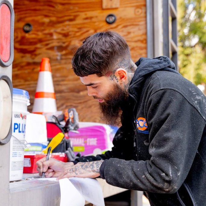 A man holds a pen, writing intently on a paper.