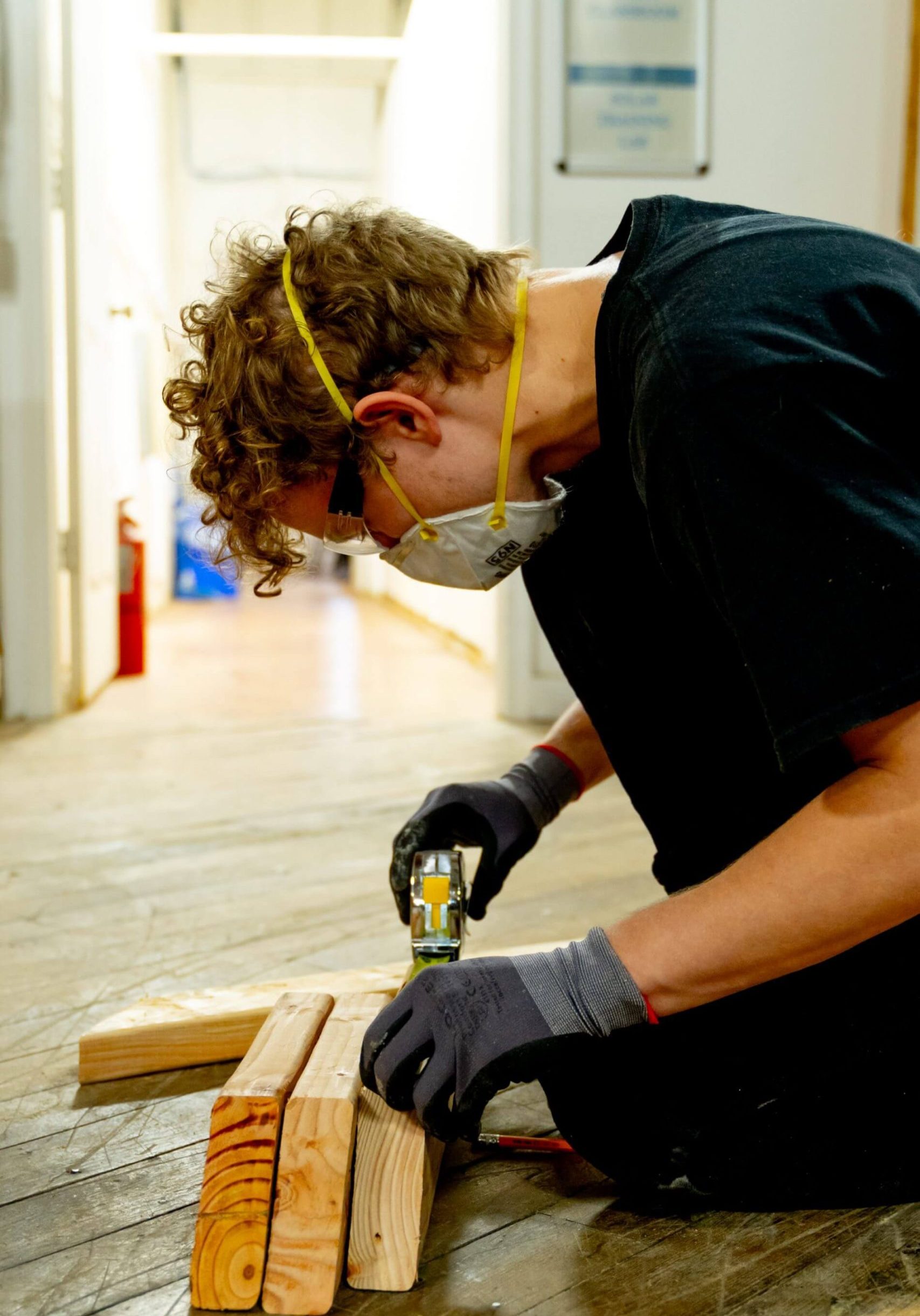 A young man carefully measure pieces of wood.