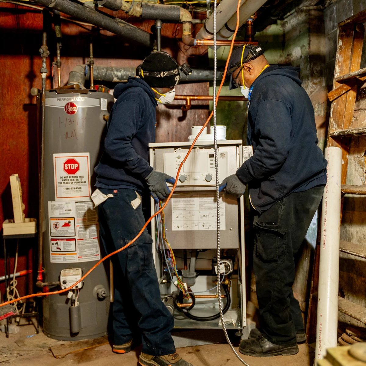 Two ECA employees fixing a heater.